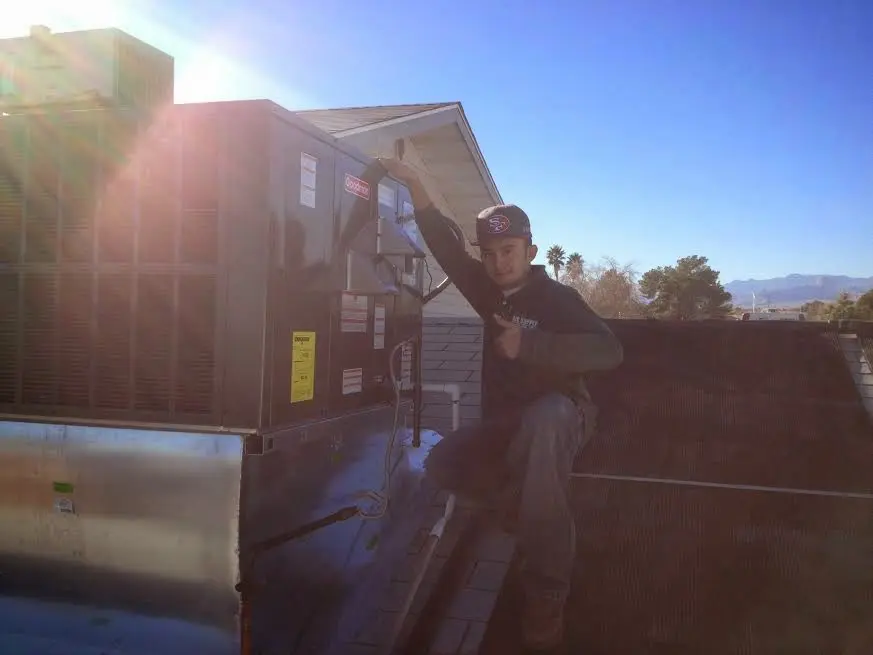 HVAC technician performing AC Tune-Up on a rooftop unit in Addison