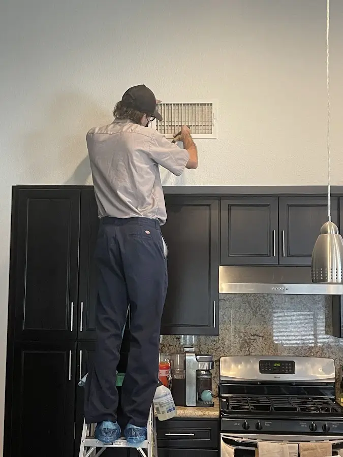Technician inspecting an air vent during HVAC service in Addison